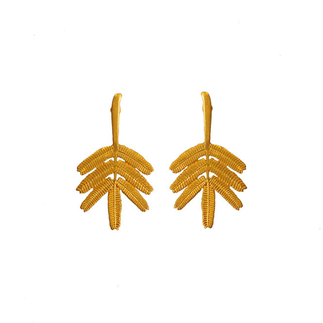 Woman wearing Dividivi branch gold earrings — artisan handmade accessory symbolizing nature, authentic style and the spirit of La Guajira